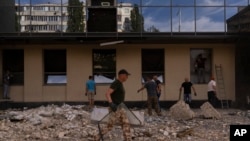 Киевде талкаланган имараттын урандыларын тазалап жаткан шаардыктар. 2-август, 2023-жыл. Иллюстрациялык сүрөт. 
