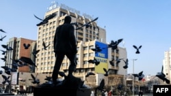 Банер на підтримку України на центральній площі Приштини. Косово, 24 лютого 2023 року. KOSOVO -- Pigeons fly in the vicinity of a large banner showing the Ukrainian flag with the words "Free Ukraine" displayed in the main square in Pristina on February 24, 2023