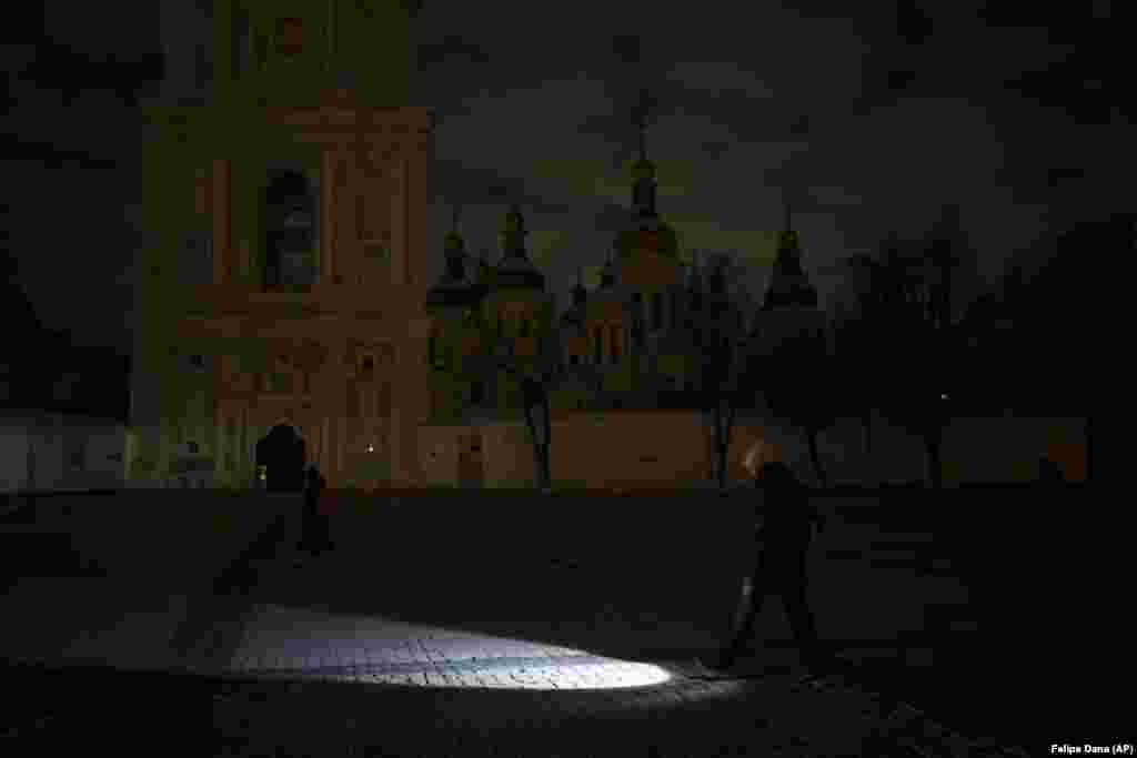 A woman walks with a flashlight during a power outage in Kyiv on December 14, 2022.