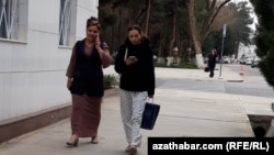 Mobile telefonda gürleşip we oňa seredip barýan zenanlar (Illýustrasiýa suraty)