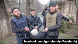 Волонтер Ігор Чорний (праворуч) з колегами евакуює жінку в Херсоні