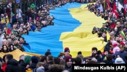 Люди несуть гігантський український прапор на знак протесту проти російського вторгнення в Україну під час святкування незалежності Литви. Вільнюс, 11 березня 2022 року