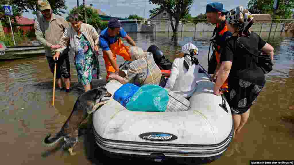Members of Russia&#39;s Emergency Ministry evacuate elderly residents with an inflatable boat on the Russian-occupied side of Kherson. &nbsp;