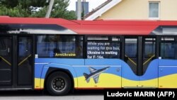 Натівський автобус з написами «Озброюйте Україну» та «Поки ви чекаєте на цей автобус, Україна чекає на F-16», припаркований біля місця проведення саміту НАТО у столиці Литви. Вільнюсі 11 липня 2023 року 