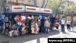 Люди біля сувенірної крамниці в центрі Феодосії напередодні початку курортного сезону, 15 квітня 2024 року