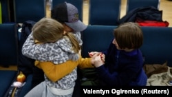 A woman holds her daughter and son, who went to a Russian-organized summer camp from nongovernment-controlled territories and were then taken to Russia, after they returned via Belarus in Kyiv in April.