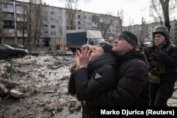 Женщина перед многоэтажным домом в ожидании спасения своего брата из-под завалов. Дом был сильно поврежден ракетным ударом российской армии. Покровск, 15 февраля 2023 года