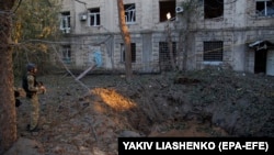 Військовослужбовець стоїть біля вирви після ракетного удару в Харкові, 21 вересня 2023 року