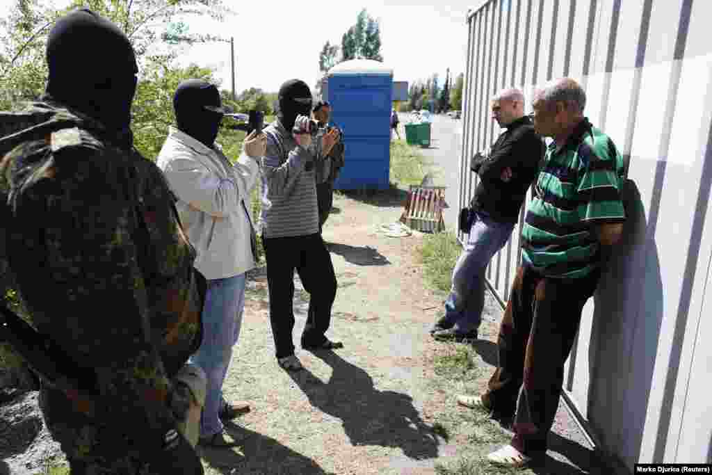 Украинские милиционеры в масках допрашивают двух мужчин на блокпосту под Мариуполем, 11 мая.&nbsp;Украинские войска установили блокпосты по периметру Мариуполя, поскольку ситуация в центре города в это время оставалась напряженной