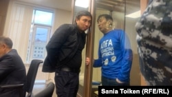 Marat Zhylanbaev (in blue) speaks from inside the defendant's enclosure during his trial in Astana in October 2023.