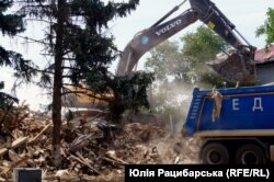 Машина вигортає руїни сільради. Село Посад-Покровське на Херсонщині, липень 2023 року