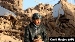 یک پسر در کنار خانه ویران شده شان در ولسوالی زنده جان ولایت هرات نشسته است در زلزله های هرات حداقل دو هزار تن جان باختند و صد ها خانه به خاک یکسان شدند