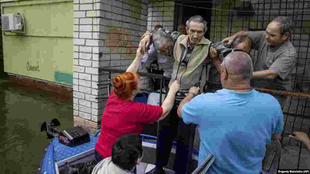 People help an elderly man onto a boat in a flooded neighborhood of Kherson.&nbsp; &nbsp;