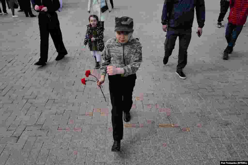 Мальчик строевым шагом подходит к вечному огню, чтобы возложить цветы