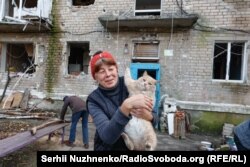 Жительница Авдеевки со спасенной кошкой возле своего многоквартирного дома, который серьезно пострадал от постоянных российских военных ударов по городу в Донецкой области Украины. Автор: Сергей Нужненко, украинская служба «Азаттыка».