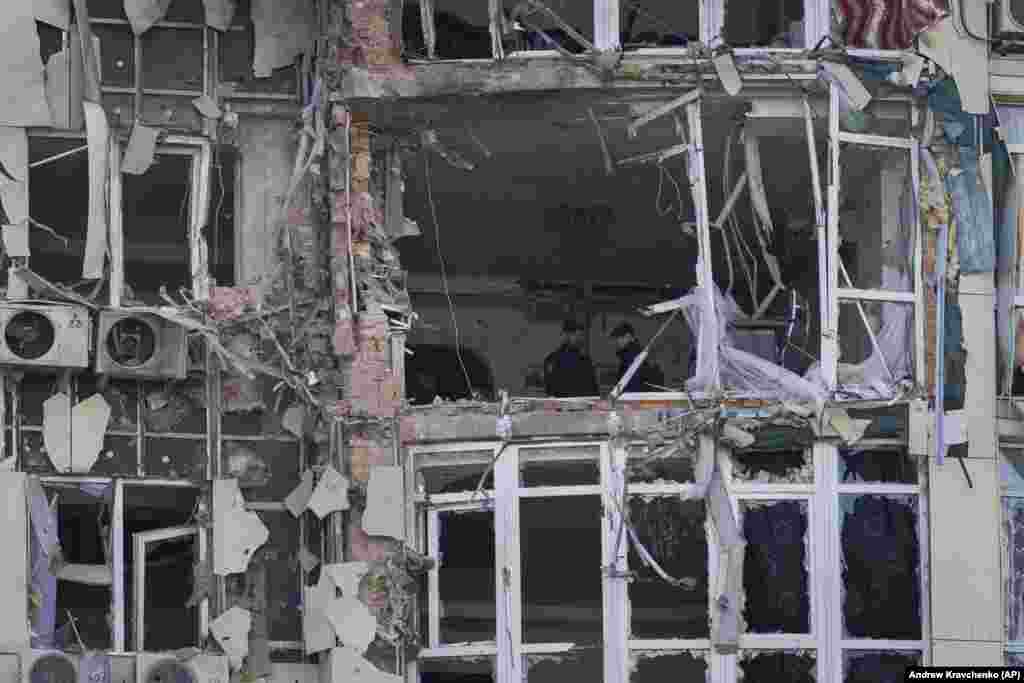 Police inspect an apartment building damaged by a drone.