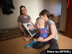 Ырысты Даурбаева с детьми. Старшие дочери показывают младшему фотографию погибшего папы Нурлыбека Асылбекова. Шымкент, 19 апреля 2023 года