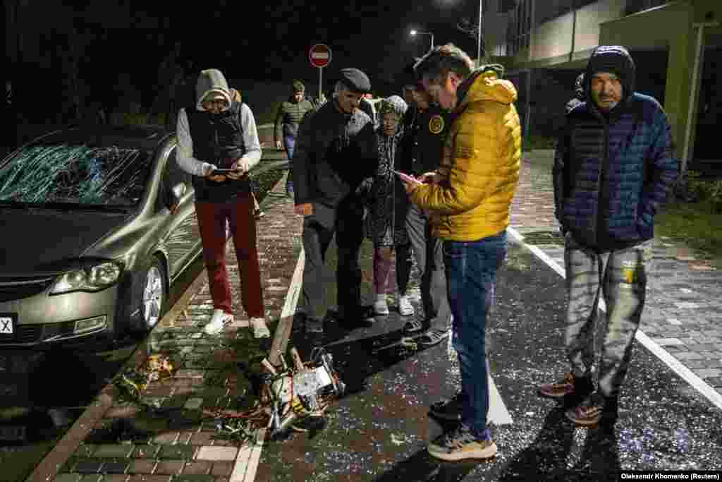 Kyiv residents inspect a part of a suicide drone -- which local authorities consider to be an Iranian-made Shahed-131/136 -- that was shot down during a Russian overnight strike.