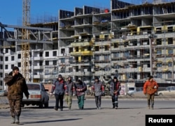 Робітники біля будови в Маріуполі, лютий 2023