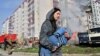 A woman carries a child past damaged residential buildings in Uman, Cherkasy region, on April 28 after Russian missile strikes targeted several Ukrainian cities overnight.
