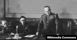 Маршал Георгий Жуков (1896–1974) 1945-жылдын 8-мартында саат 22:00ден кийин Берлиндин жанындагы Карлхорст шаарчасында Германиянын шартсыз багынып берүүсү тууралуу актты окуп жатат.