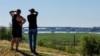 Two men look toward the Antonivskiy Bridge across the Dnieper River in the Russian-controlled Ukrainian city of Kherson after a Ukrainian air strike hit the bridge, forcing authorities to close it on July 27.