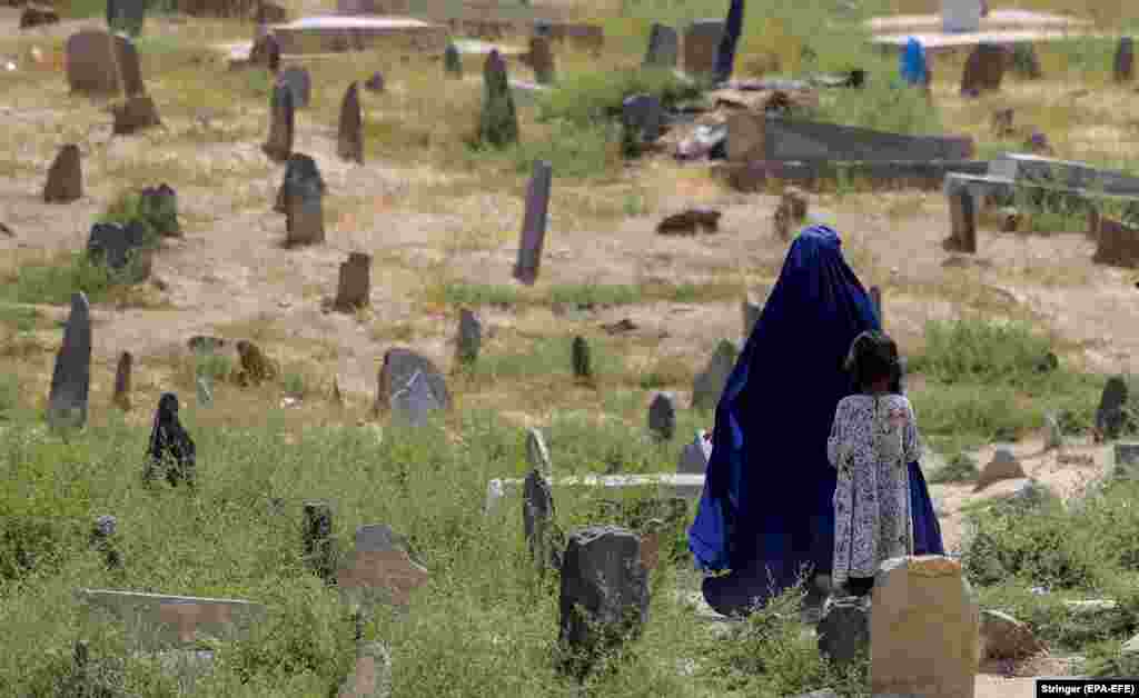 Кабулдагы көрүстөндө паранжа кийген ооган аял менен бала зыярат кылып жүрүшөт.