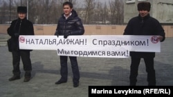 Активисты держат плакат с надписью "Наталья, Айжан! С праздником! Мы гордимся вами!", посвященный заключенным активисткам Наталье Соколовой и Айжангуль Амировой.  Семей, 7 марта 2012 года.