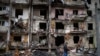 FILE - A man walks past a building damaged following a rocket attack, in Kyiv, Ukraine, Friday, Feb. 25, 2022.  The International Criminal Court's prosecutor has put combatants and their commanders on notice that he is monitoring Russia's invasion of Ukra