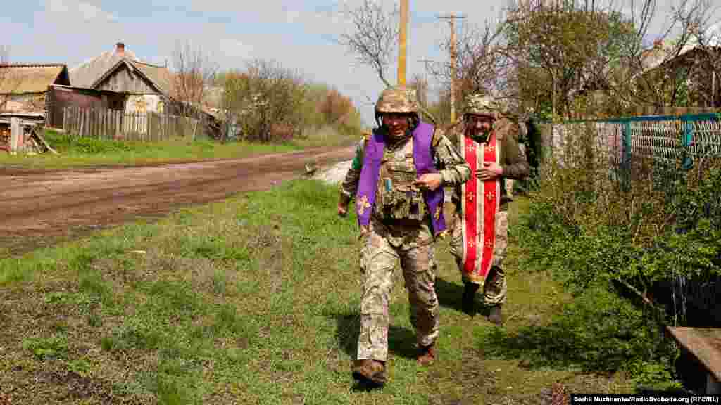 Військові капелани Максим та Олександр ідуть фронтовим селом, щоб відправити Великоднє богослужіння для українських військових на позиціях. Харківська область, 24 квітня 2022 року