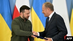 Президент України Володимир Зеленський (ліворуч) тисне руку прем’єр-міністру Польщі Дональду Туску після підписання безпекової угоди у Варшаві, Польща, 8 липня 2024 року