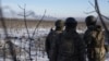 Ukrainian soldiers watch as smoke billows during heavy fighting in Soledar in the Donetsk region on January 11. 