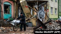 A local resident pushes his bicycle past "hedgehog" tank traps and rubble down a street in Bakhmut, in the Donetsk region, on January 6.