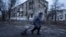 A local woman walks to the distribution point of humanitarian aid in front of housing that was damaged by Russian shelling in Kupyansk, in Ukraine's Kharkiv region, on December 28.