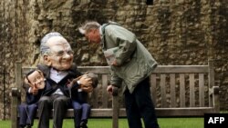 Участник антиправительственной демонстрации в маске Руперта Мердока с марионетками Дэвида Кэмерона и Джереми Ханта в руках