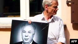 Человек в портретом Михаила Головатова перед посольством в Австрии в Вильнюсе, 18 июля 2011