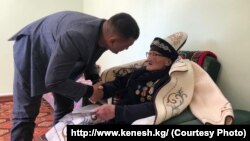 Согуштун ардагери, 97 жаштагы Шарше Исраиловду ЖК депутаты Максатбек Сарбагышев куттуктоодо.