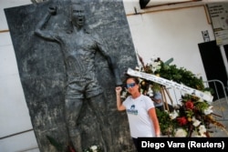 Прыхільніца футболу фатаграфуецца на фоне барэльефу Пэле каля стадыёну «Віла Бэльміра» ў Сантусе