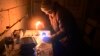 An elderly woman lights a candle in her apartment in a residential building partially destroyed as a result of Russian shelling in the village of Gorenka in the Kyiv region on December 13.