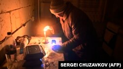 An elderly woman lights a candle in her apartment in a residential building partially destroyed as a result of Russian shelling in the village of Gorenka in the Kyiv region on December 13.