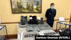 Көргөзмөдө: полициянын талкаланган калкандары жана башаламандыкка катышкандардан тартып алынган курал-жарак (Ички иштер министрлигинин жоромолу боюнча). Булар күч түзүмдөрүнүн башчылары отчёт берген күнү Мажилиске алып келинди.