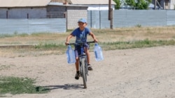 Мальчик везет воду на велосипеде. Село Кызылсуат. Акмолинская область, 10 июня 2020 года.