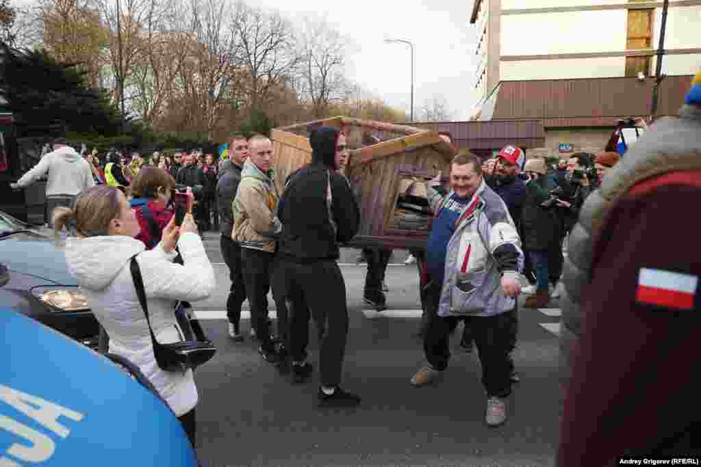 Несколько мужчин несут на акцию протеста большую собачью конуру