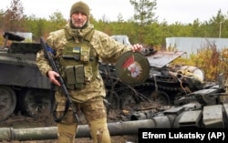 Військовослужбовець України показує емблему елітного підрозділу військ Росії біля знищених російських танків у селі Дмитрівка під Києвом, 2 квітня 2022 року