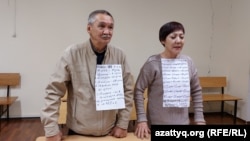 Гражданские активисты Маруа Ескендирова и Амангельды Оразбаев на суде по их делу  с плакатами, на которых перечислены сутки, в которые они в разное время отбывали административные аресты. Уральск, 7 октября 2022 года