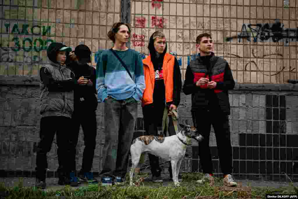 Молодые люди смотрят на разрушения после ракетного удара. По информации украинских СМИ, ударам подверглись по меньшей мере 16 городов. Многие из них не обстреливались с весны&nbsp;&nbsp;