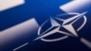 Лягатып NATO на фоне сьцягу Фінляндыі 