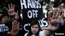Люди показують свої долоні, на яких написано «Ні», в знак протесту проти накладання податку на депозити в банках Кіпру, 18 березня 2013 року