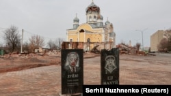 Надмагільлі з партрэтамі Пуціна і Лукашэнкі перад пашкоджанай абстрэламі царквой у горадзе Малын (Жытомірская вобласьць), што ў 100 км ад беларускай мяжы. 30 сакавіка 2022 