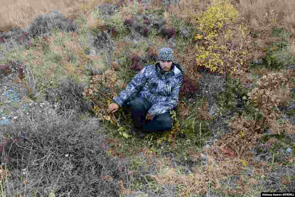 В этих же местах обнаружены и другие артефакты древности, кроме петроглифов &ndash; разграбленные курганы-захоронения, оградки для жилищ, древние тропы, ямы искусственного происхождения. Ученых это наводит на предположения, что здесь могло быть поселение охотников на древнем пути через горы. На этом фото Бекбол Нурмуханбетов сидит в яме искусственного происхождения глубиной чуть больше метра. Бекбол предположил, что это схрон древних охотников на горных козлов и других диких животных.